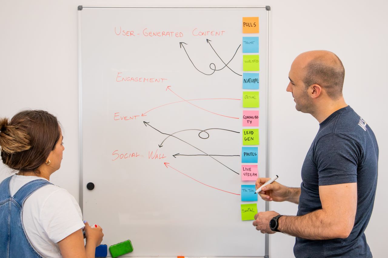 services-03 Two colleagues brainstorm ideas on a whiteboard during a creative strategy session.